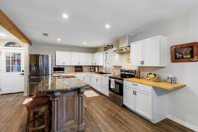 2340 E State Highway 71, Llano, TX 78643 - kitchen with appliances with stainless steel finishes, dark wood-style flooring, a breakfast bar, a sink, and white cabinetry