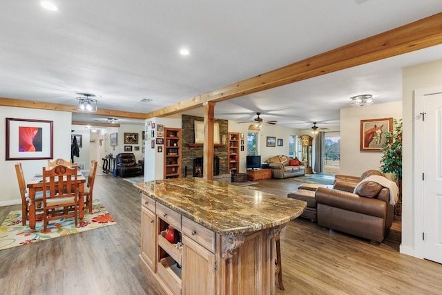 2340 E State Highway 71, Llano, TX 78643 - kitchen with open floor plan, light wood-style flooring, a stone fireplace, dark stone countertops, and ceiling fan