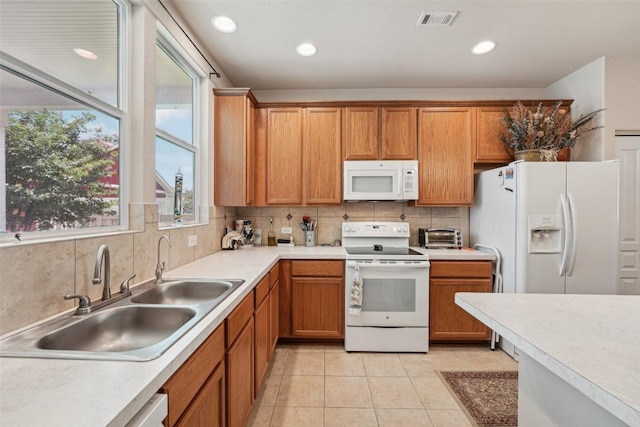 1261 Nevarez, Kyle, TX 78640 - kitchen featuring white appliances, tasteful backsplash, light countertops, brown cabinetry, and light tile patterned flooring