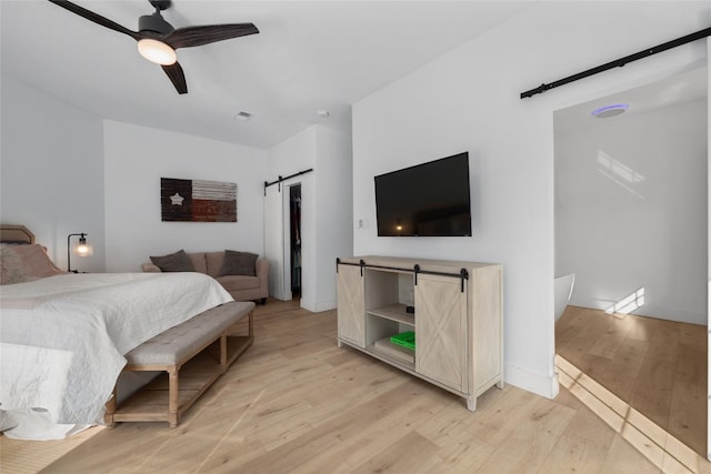 120 Acapulco Dr, Lakeway, TX 78734 - bedroom with a barn door, light wood-style flooring, and a ceiling fan