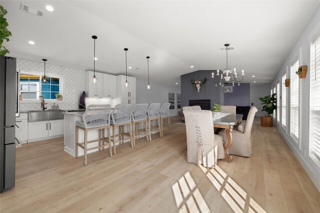 120 Acapulco Dr, Lakeway, TX 78734 - dining space with light wood-style flooring, plenty of natural light, a chandelier, vaulted ceiling, and a large fireplace