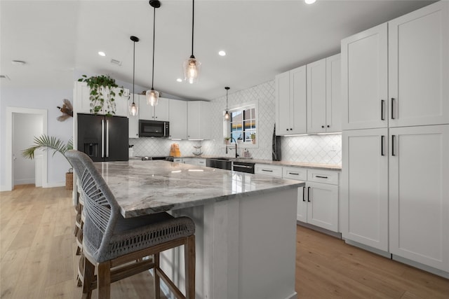 120 Acapulco Dr, Lakeway, TX 78734 - kitchen with refrigerator with ice dispenser, black microwave, lofted ceiling, decorative backsplash, and a center island