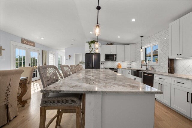 120 Acapulco Dr, Lakeway, TX 78734 - kitchen featuring black fridge, dishwashing machine, vaulted ceiling, tasteful backsplash, and healthy amount of natural light