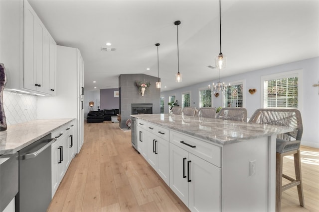 120 Acapulco Dr, Lakeway, TX 78734 - kitchen with dishwasher, a breakfast bar, light wood-style flooring, a fireplace, and recessed lighting