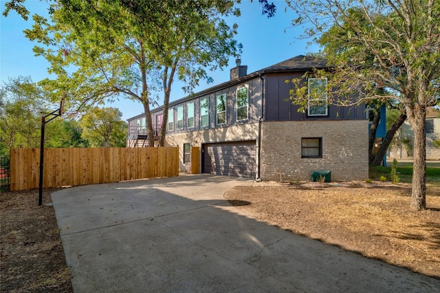 120 Acapulco Dr, Lakeway, TX 78734 - view of property exterior featuring driveway, an attached garage, a chimney, and board and batten siding