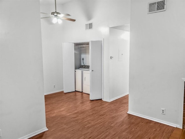 106 E 30th St Unit 305, Austin, TX 78705 - spare room with washer and clothes dryer, baseboards, ceiling fan, wood finished floors, and a high ceiling