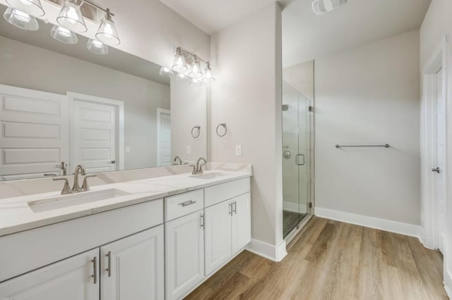 21710 Patton Dr, Lago Vista, TX 78645 - full bathroom with double vanity, a shower stall, wood finished floors, and baseboards