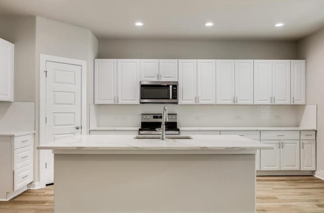 21710 Patton Dr, Lago Vista, TX 78645 - kitchen featuring stainless steel appliances, a sink, light wood-type flooring, white cabinetry, and recessed lighting
