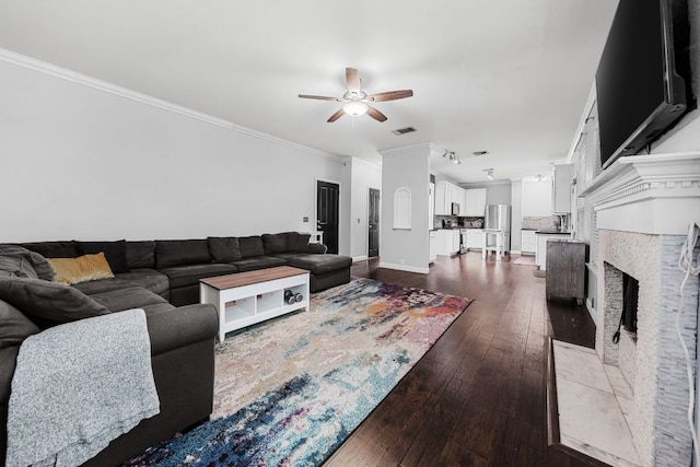 1600 Serenity Springs Cv, Cedar Park, TX 78613 - living area featuring ceiling fan, crown molding, dark wood-style floors, a fireplace with flush hearth, and baseboards
