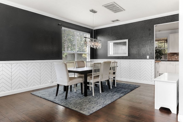 1600 Serenity Springs Cv, Cedar Park, TX 78613 - dining room with crown molding, a wainscoted wall, dark wood-style floors, wallpapered walls, and a chandelier