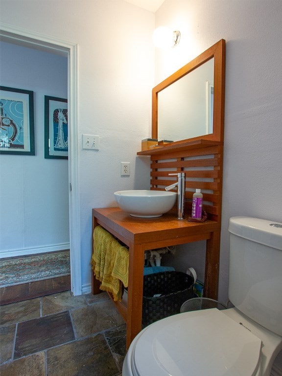 1808 Maple Ave, Austin, TX 78702 - bathroom with stone finish flooring, toilet, vanity, and baseboards