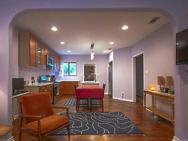 1808 Maple Ave, Austin, TX 78702 - kitchen with appliances with stainless steel finishes, brown cabinets, light countertops, arched walkways, and recessed lighting