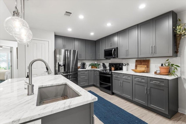 2003 Rain Water Dr, Austin, TX 78734 - kitchen featuring appliances with stainless steel finishes, gray cabinets, light stone countertops, decorative backsplash, and light wood-style flooring