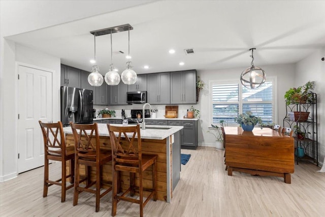 2003 Rain Water Dr, Austin, TX 78734 - kitchen featuring stainless steel appliances, gray cabinets, light wood-style flooring, a center island with sink, and recessed lighting