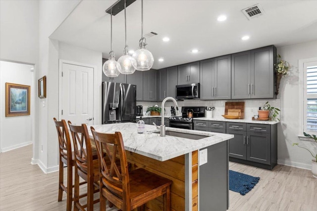2003 Rain Water Dr, Austin, TX 78734 - kitchen featuring appliances with stainless steel finishes, gray cabinetry, light stone counters, light wood-style floors, and recessed lighting