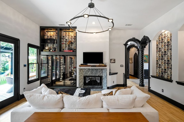 2621 Exposition Blvd, Austin, TX 78703 - living room featuring a dry bar, wood finished floors, a premium fireplace, a chandelier, and arched walkways