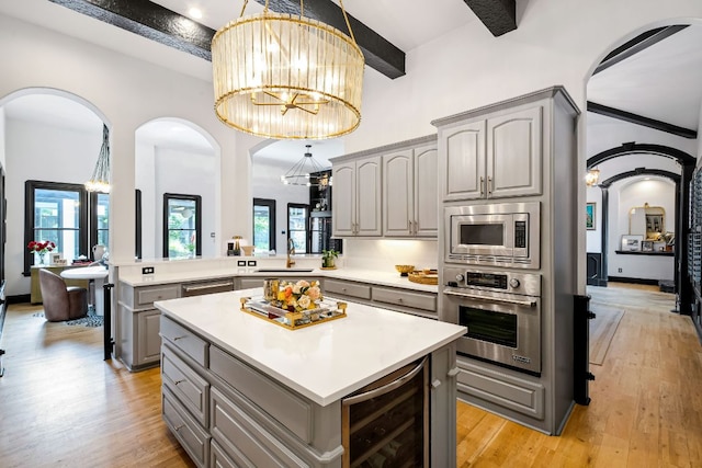 2621 Exposition Blvd, Austin, TX 78703 - kitchen with gray cabinetry, beverage cooler, stainless steel appliances, a chandelier, and arched walkways