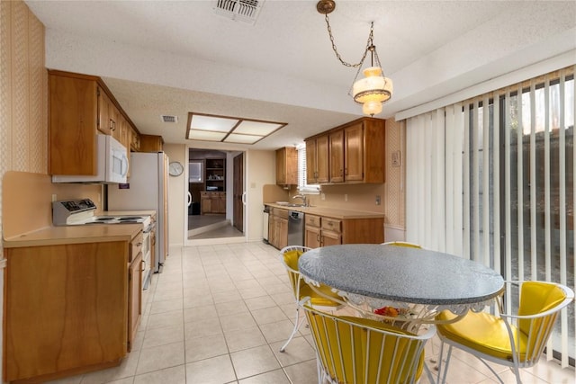6203 Shadow Mountain Cv, Austin, TX 78731 - kitchen with white appliances, light countertops, brown cabinetry, light tile patterned floors, and wallpapered walls