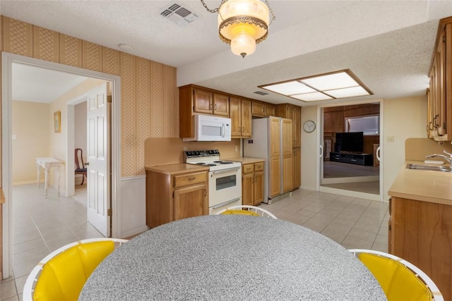 6203 Shadow Mountain Cv, Austin, TX 78731 - kitchen featuring white appliances, light tile patterned floors, wallpapered walls, a textured ceiling, and a sink