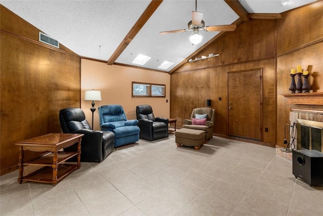 6203 Shadow Mountain Cv, Austin, TX 78731 - living room with light tile patterned floors, wood walls, beamed ceiling, ceiling fan, and a brick fireplace