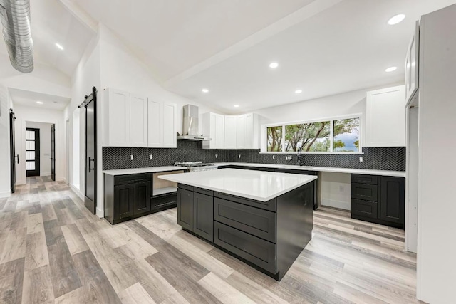 4190 W Fm 243, Bertram, TX 78605 - kitchen featuring a barn door, wall chimney range hood, white cabinetry, tasteful backsplash, and a center island