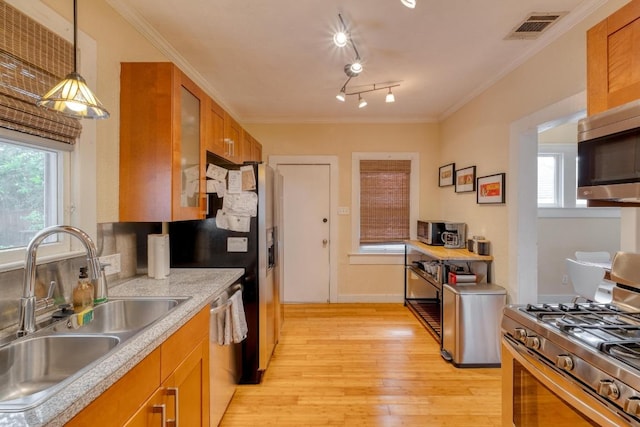 1706 Pennsylvania Ave, Austin, TX 78702 - kitchen featuring stainless steel appliances, brown cabinetry, light wood-type flooring, light countertops, and glass insert cabinets