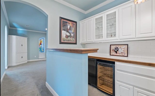 762 S Guadalupe St, Lockhart, TX 78644 - indoor dry bar featuring beverage cooler, arched walkways, ornamental molding, baseboards, and light carpet