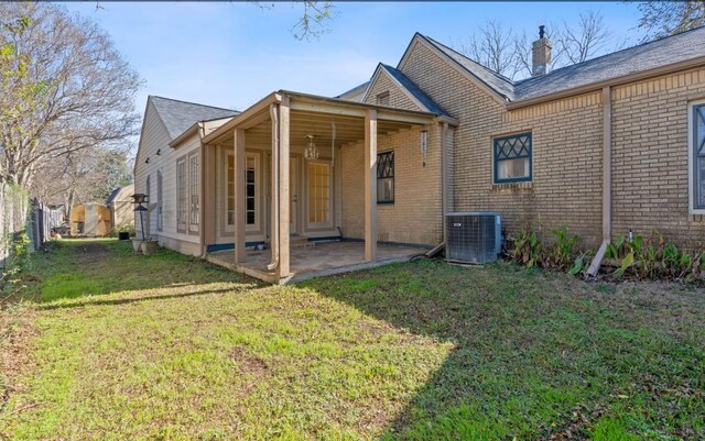 762 S Guadalupe St, Lockhart, TX 78644 - back of property featuring central AC unit, a patio area, brick siding, a yard, and a chimney