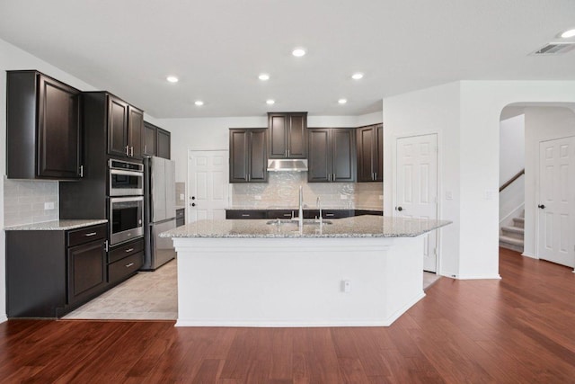 104 Kulmbacher Dr, Austin, TX 78728 - kitchen with a sink, appliances with stainless steel finishes, tasteful backsplash, a center island with sink, and light wood finished floors