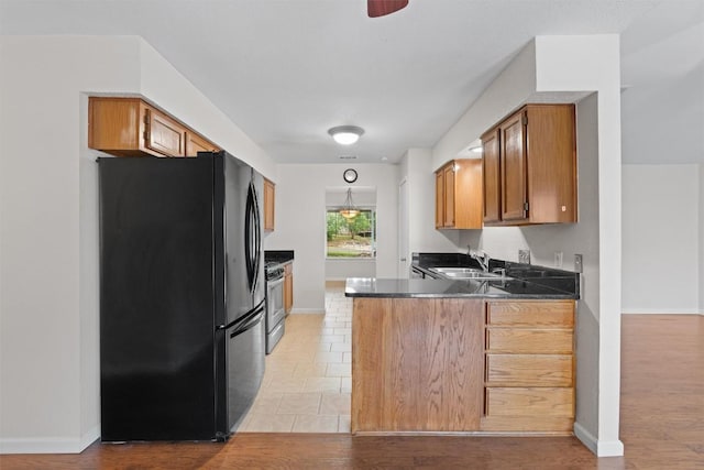 8407 Bargamin Dr, Austin, TX 78736 - kitchen featuring freestanding refrigerator, a sink, a peninsula, and brown cabinetry