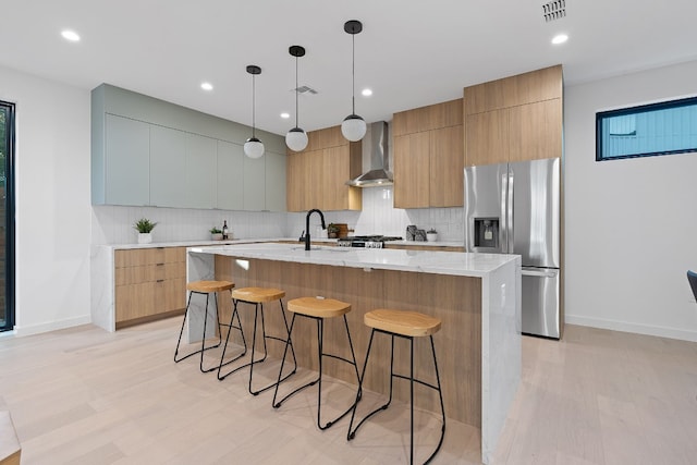 2704 Canterbury St Unit A, Austin, TX 78702 - kitchen featuring stainless steel refrigerator with ice dispenser, wall chimney range hood, modern cabinets, a kitchen bar, and baseboards