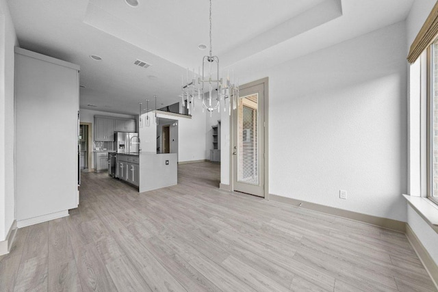 8108 Turning Leaf Cir, Lago Vista, TX 78645 - unfurnished living room with a chandelier, baseboards, light wood-style floors, and a raised ceiling
