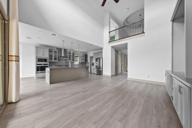 8108 Turning Leaf Cir, Lago Vista, TX 78645 - unfurnished living room with a ceiling fan, light wood-style flooring, baseboards, and a high ceiling