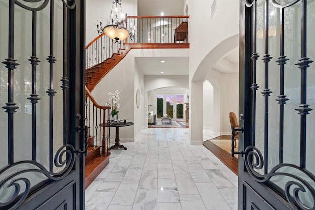 512 Newhall Cv, Austin, TX 78746 - entrance foyer with arched walkways, a towering ceiling, stairs, baseboards, and light marble finish flooring