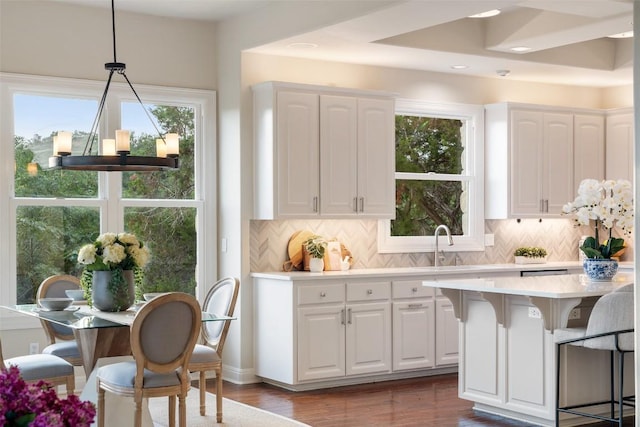 512 Newhall Cv, Austin, TX 78746 - kitchen with light countertops, a kitchen breakfast bar, white cabinets, tasteful backsplash, and recessed lighting