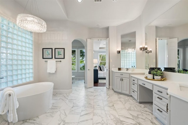 512 Newhall Cv, Austin, TX 78746 - ensuite bathroom with a freestanding bath, vanity, a chandelier, marble look tile flooring, and baseboards