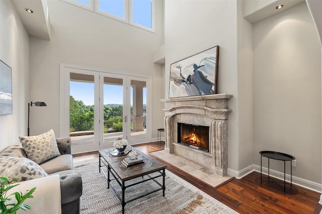 512 Newhall Cv, Austin, TX 78746 - living area with french doors, wood-type flooring, a premium fireplace, healthy amount of natural light, and a high ceiling