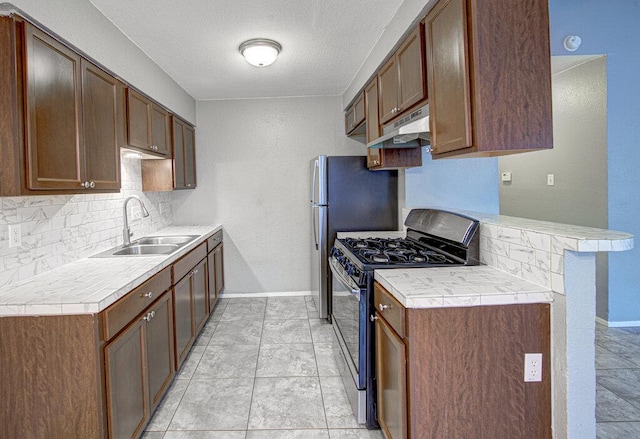 4401 Teri Rd, Austin, TX 78744 - kitchen featuring range with gas cooktop, a sink, under cabinet range hood, decorative backsplash, and baseboards