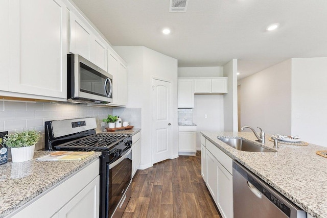 208 Charles Trl, Georgetown, TX 78626 - kitchen with appliances with stainless steel finishes, a sink, dark wood-style flooring, white cabinetry, and light stone countertops
