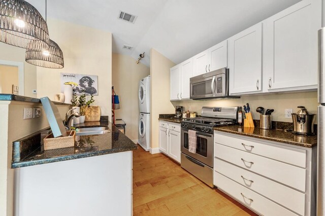 111 Adam L Chapa Sr St, Austin, TX 78702 - kitchen with appliances with stainless steel finishes, estacked washer and dryer, lofted ceiling, light wood finished floors, and white cabinets