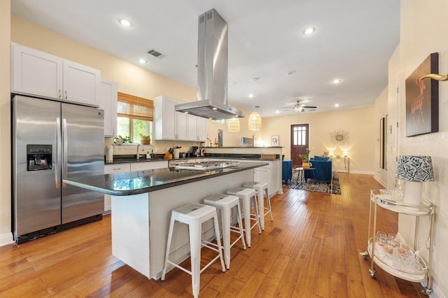 111 Adam L Chapa Sr St, Austin, TX 78702 - kitchen with stainless steel fridge with ice dispenser, island exhaust hood, dark countertops, healthy amount of natural light, and recessed lighting