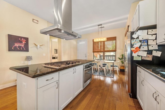 111 Adam L Chapa Sr St, Austin, TX 78702 - kitchen featuring island exhaust hood, stainless steel appliances, hardwood / wood-style flooring, white cabinetry, and decorative light fixtures