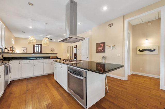 111 Adam L Chapa Sr St, Austin, TX 78702 - kitchen with stainless steel appliances, island exhaust hood, white cabinets, light wood-type flooring, and ceiling fan