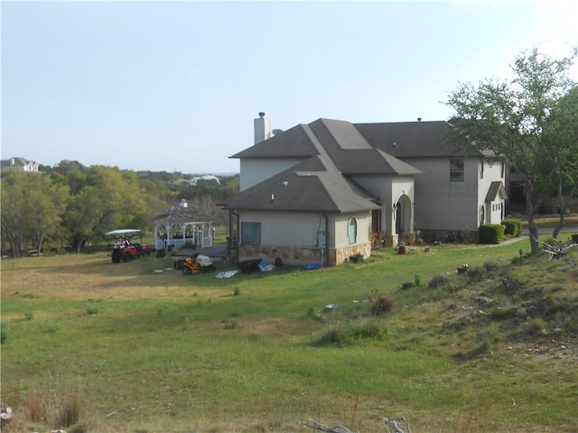 159 Catfish Cv, Dripping Springs, TX 78620 - back of house with a chimney, a yard, and stucco siding
