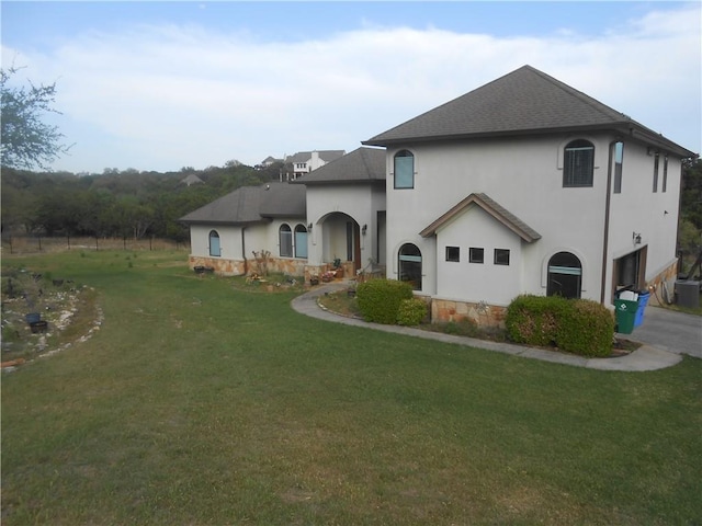159 Catfish Cv, Dripping Springs, TX 78620 - rear view of property featuring stucco siding, a shingled roof, and a lawn
