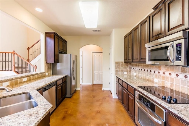 159 Catfish Cv, Dripping Springs, TX 78620 - kitchen with stainless steel appliances, arched walkways, concrete flooring, a sink, and tasteful backsplash