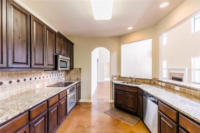 159 Catfish Cv, Dripping Springs, TX 78620 - kitchen featuring stainless steel appliances, a sink, arched walkways, tasteful backsplash, and concrete floors