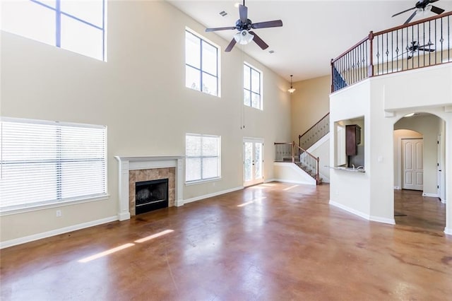 159 Catfish Cv, Dripping Springs, TX 78620 - unfurnished living room featuring ceiling fan, a high ceiling, finished concrete floors, arched walkways, and a tile fireplace