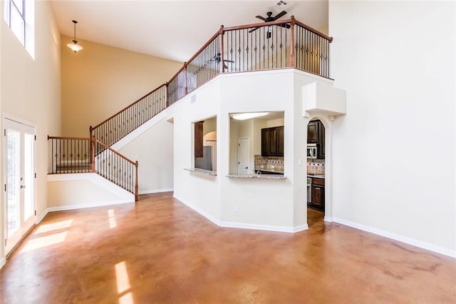 159 Catfish Cv, Dripping Springs, TX 78620 - unfurnished living room with concrete flooring, a high ceiling, a ceiling fan, stairway, and baseboards
