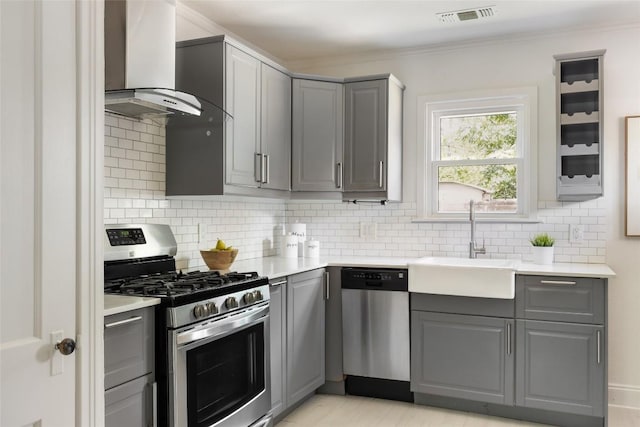 5306 Harmon Ave, Austin, TX 78751 - kitchen featuring appliances with stainless steel finishes, gray cabinets, wall chimney exhaust hood, and crown molding